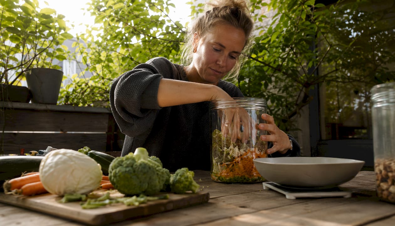 En kvinde står i sit køkken og laver hjemmelavet fermenteret hundefoder.