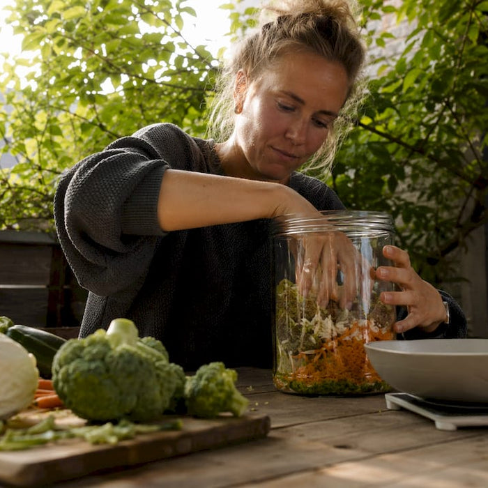 En kvinde står i sit køkken og laver hjemmelavet fermenteret hundefoder.